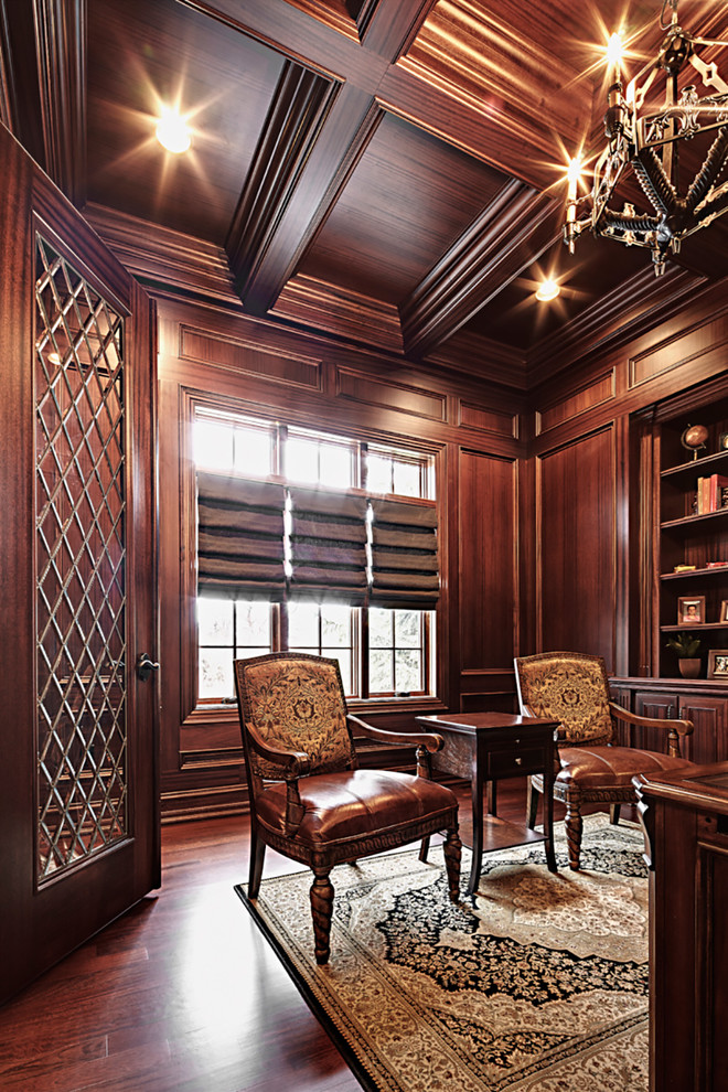 Ejemplo de despacho tradicional grande con paredes marrones, suelo de madera oscura y escritorio independiente