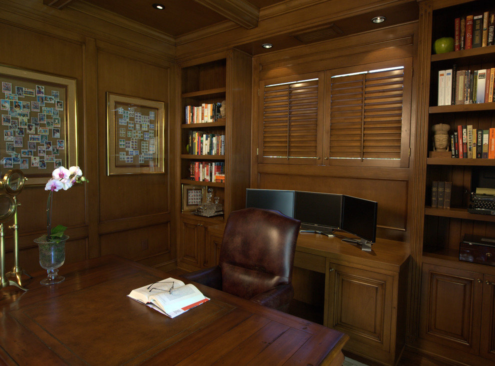 Diseño de despacho clásico grande sin chimenea con paredes marrones, suelo de madera oscura y escritorio independiente