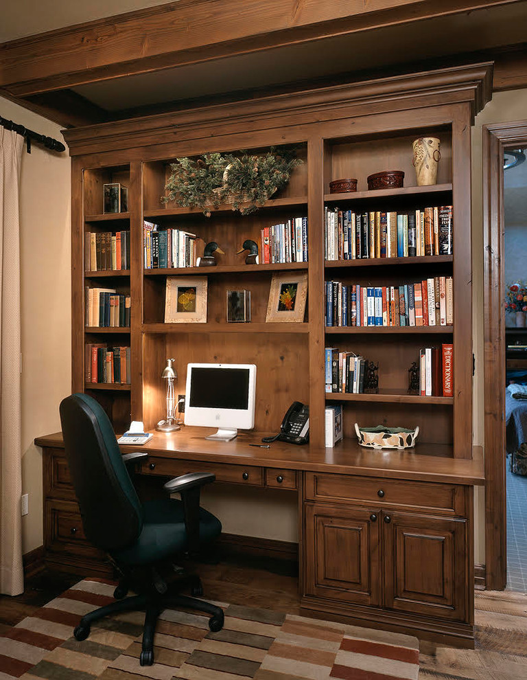 На фото: домашняя библиотека среднего размера в стиле рустика с бежевыми стенами, паркетным полом среднего тона, отдельно стоящим рабочим столом и коричневым полом без камина с