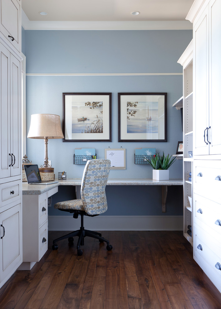Diseño de despacho tradicional con paredes azules, suelo de madera oscura y escritorio empotrado