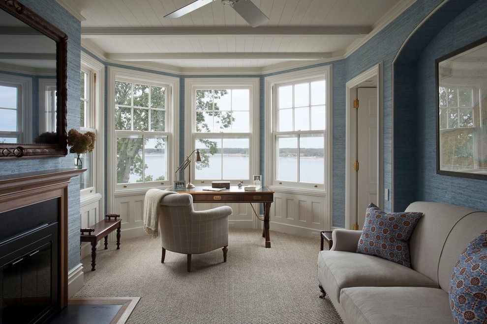 ニューヨークにある高級な中くらいなトラディショナルスタイルのおしゃれな書斎 (青い壁、カーペット敷き、標準型暖炉、金属の暖炉まわり、自立型机、ベージュの床) の写真