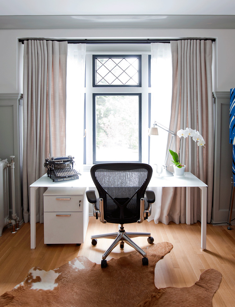 Idee per un ufficio chic con pareti bianche, pavimento in legno massello medio e scrivania autoportante