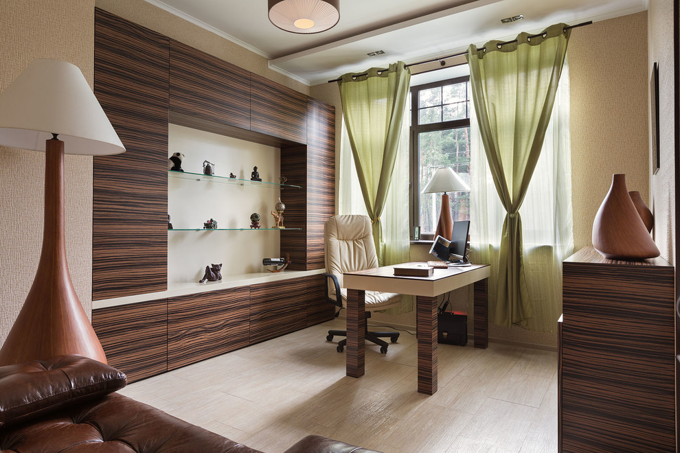 Ejemplo de despacho actual de tamaño medio con paredes beige, suelo de madera clara y escritorio independiente