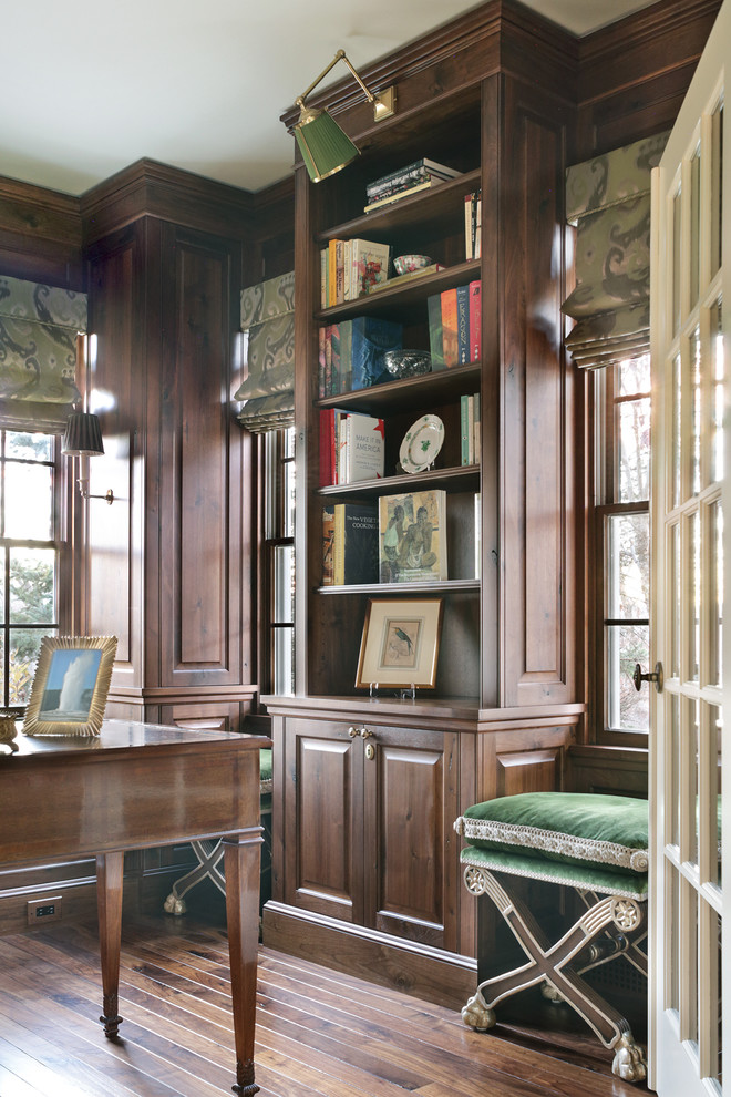 Foto de despacho clásico pequeño sin chimenea con biblioteca, paredes marrones, suelo de madera oscura, escritorio independiente y suelo marrón