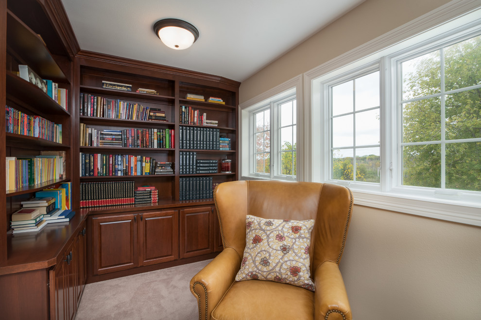 Klassisk inredning av ett litet arbetsrum, med ett bibliotek, beige väggar, heltäckningsmatta, ett inbyggt skrivbord och beiget golv