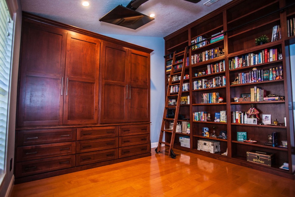 Idée de décoration pour un bureau tradition de taille moyenne avec une bibliothèque ou un coin lecture, un mur bleu, un sol en bois brun, aucune cheminée, un bureau intégré et un sol marron.