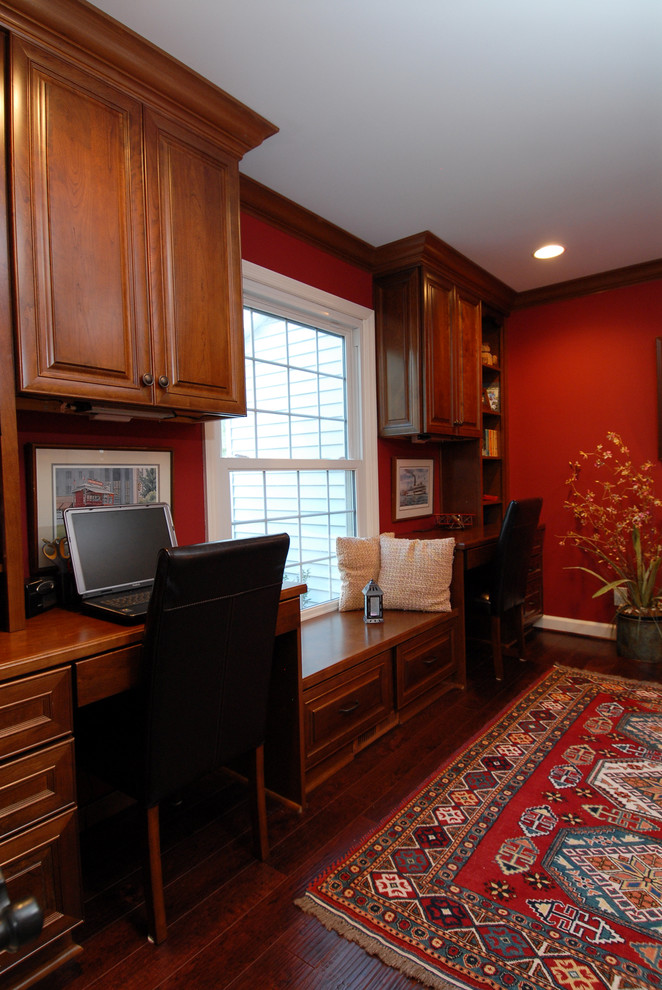 Example of a mid-sized classic built-in desk dark wood floor and brown floor study room design in Columbus with red walls and no fireplace