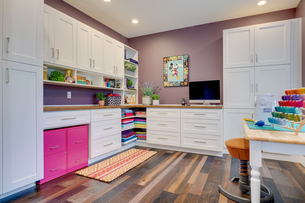 Inspiration pour un grand bureau atelier traditionnel avec un mur violet, parquet foncé, aucune cheminée, un bureau intégré et un sol marron.
