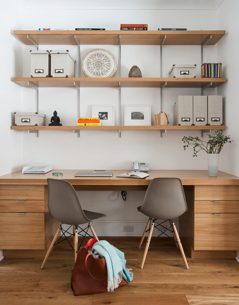 Modelo de despacho clásico renovado de tamaño medio con paredes blancas, suelo de madera en tonos medios y escritorio independiente