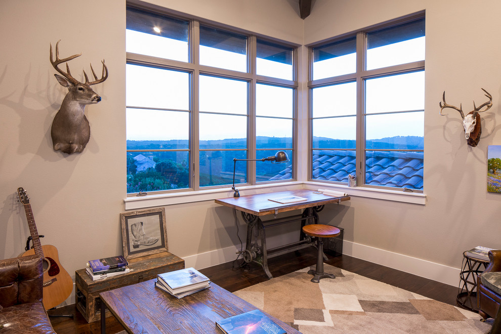 Mittelgroßes Country Arbeitszimmer ohne Kamin mit Arbeitsplatz, beiger Wandfarbe, dunklem Holzboden und freistehendem Schreibtisch in Austin