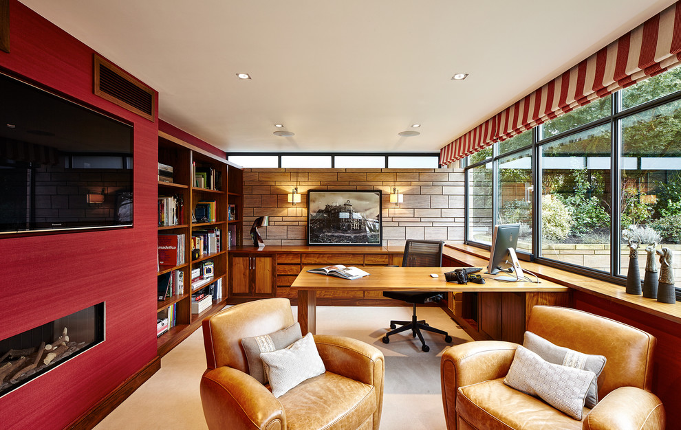 他の地域にあるトランジショナルスタイルのおしゃれな書斎 (赤い壁、カーペット敷き、横長型暖炉、造り付け机) の写真
