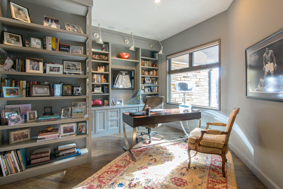 Esempio di uno studio chic di medie dimensioni con libreria, pareti grigie, parquet scuro, scrivania autoportante e pavimento marrone