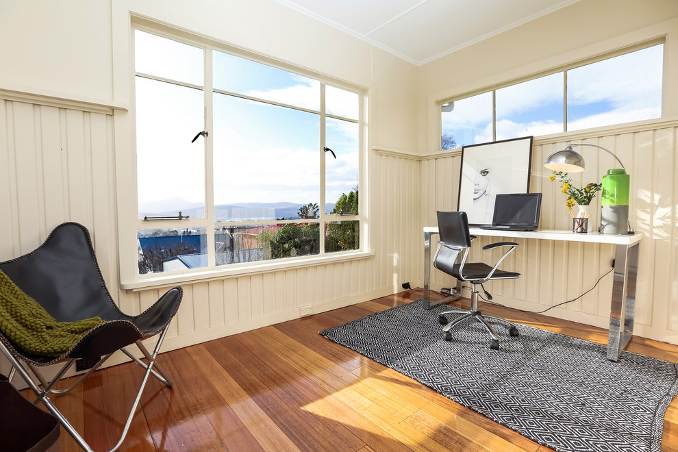 Diseño de despacho clásico renovado pequeño con paredes beige, suelo de madera en tonos medios y escritorio independiente