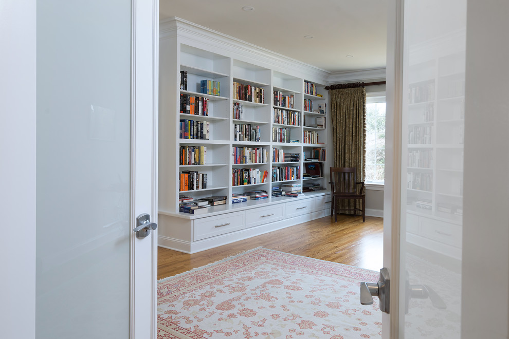 Immagine di un grande studio classico con libreria, pareti grigie, pavimento in legno massello medio, scrivania autoportante e pavimento marrone