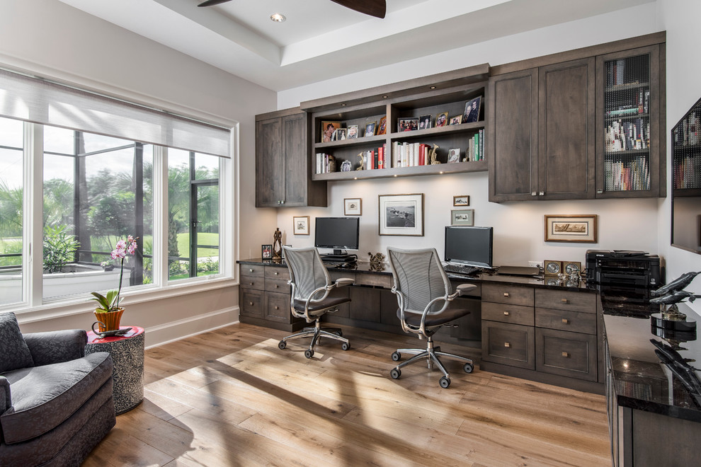 Foto de despacho clásico renovado de tamaño medio con paredes grises, suelo de madera clara y escritorio empotrado