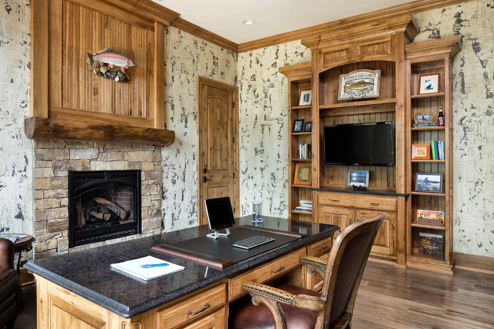 Large mountain style built-in desk medium tone wood floor study room photo in Kansas City with white walls, a standard fireplace and a stone fireplace