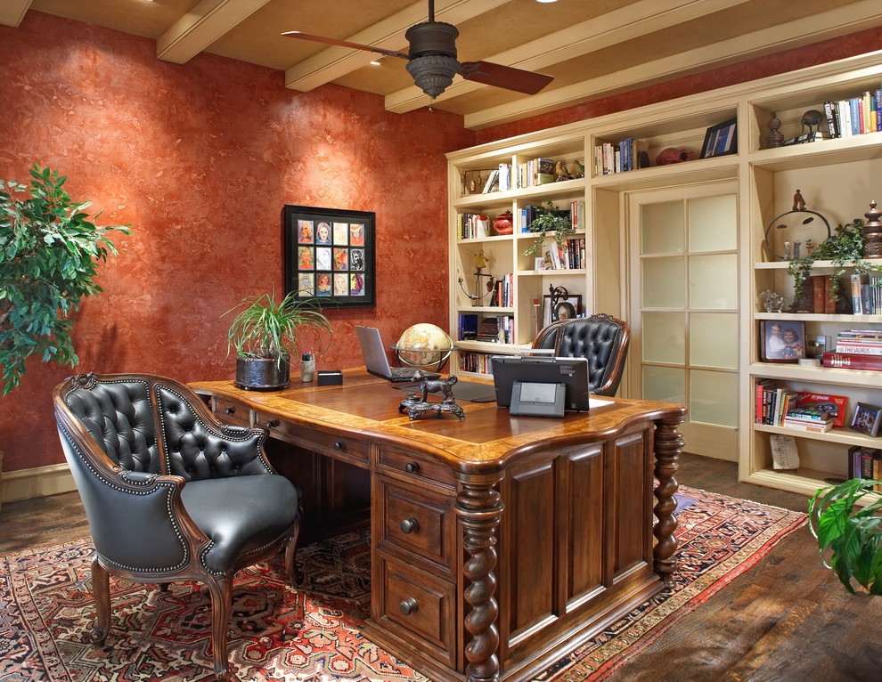 Inspiration för mellanstora klassiska hemmabibliotek, med röda väggar, mörkt trägolv och ett fristående skrivbord