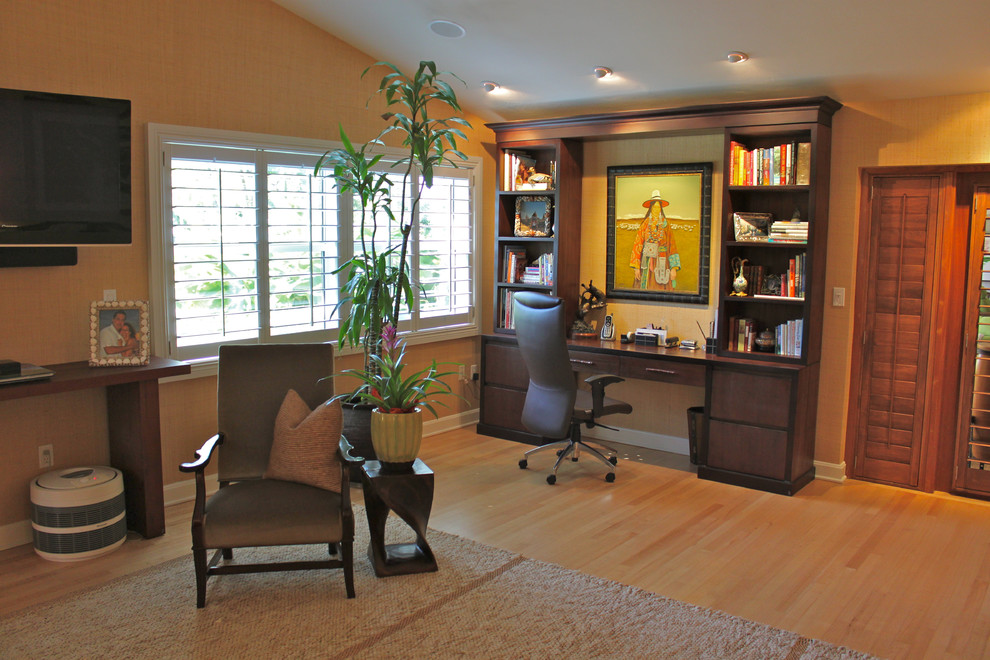 Diseño de despacho tropical con parades naranjas, suelo de madera en tonos medios y escritorio empotrado