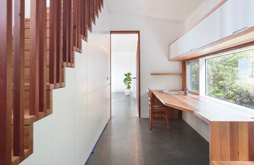 Свежая идея для дизайна: домашняя мастерская среднего размера в морском стиле с белыми стенами, бетонным полом, встроенным рабочим столом и серым полом без камина - отличное фото интерьера