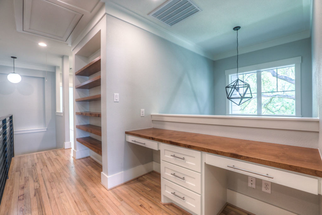 Example of a mid-sized mid-century modern built-in desk medium tone wood floor and brown floor home office design in Houston with gray walls