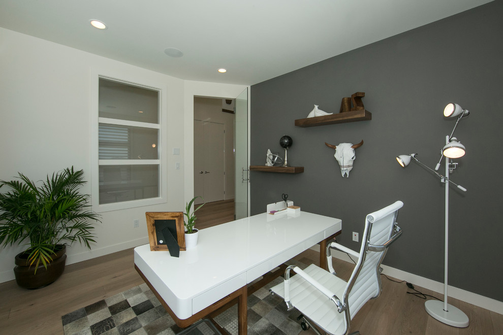 Immagine di un ufficio design di medie dimensioni con pareti grigie, parquet chiaro e scrivania autoportante