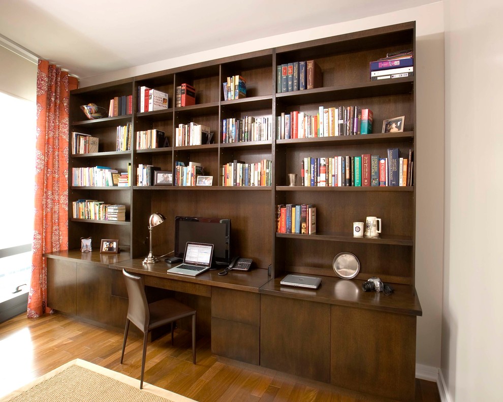 Example of a mid-sized minimalist built-in desk medium tone wood floor study room design in New York with no fireplace