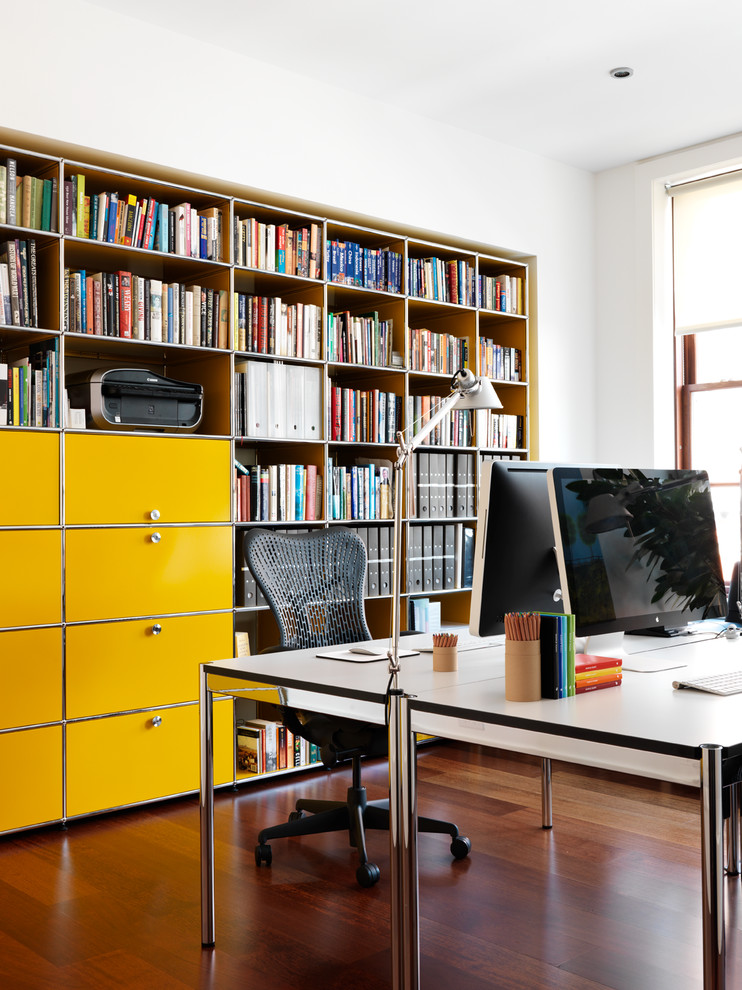 Example of a large trendy freestanding desk medium tone wood floor study room design in New York with white walls