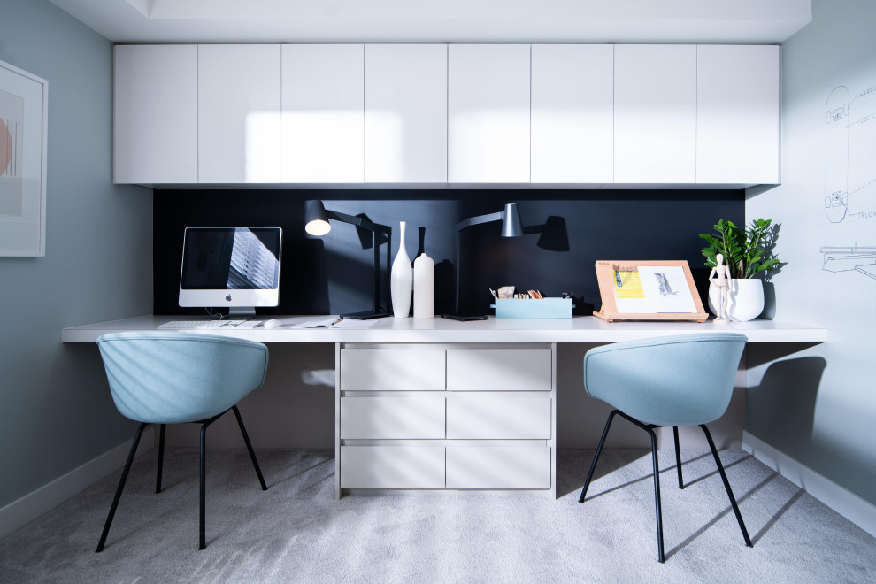 Modelo de despacho nórdico de tamaño medio con paredes azules, moqueta, escritorio empotrado y suelo beige
