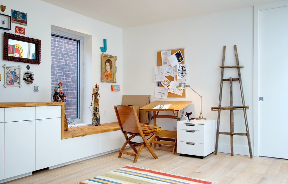 Eklektisk inredning av ett hemmastudio, med vita väggar och ljust trägolv