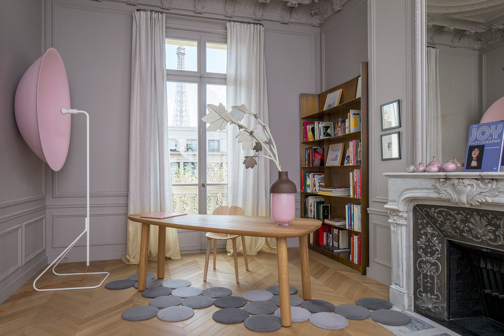 Foto på ett vintage hemmabibliotek, med grå väggar, ljust trägolv, en standard öppen spis, ett fristående skrivbord och brunt golv