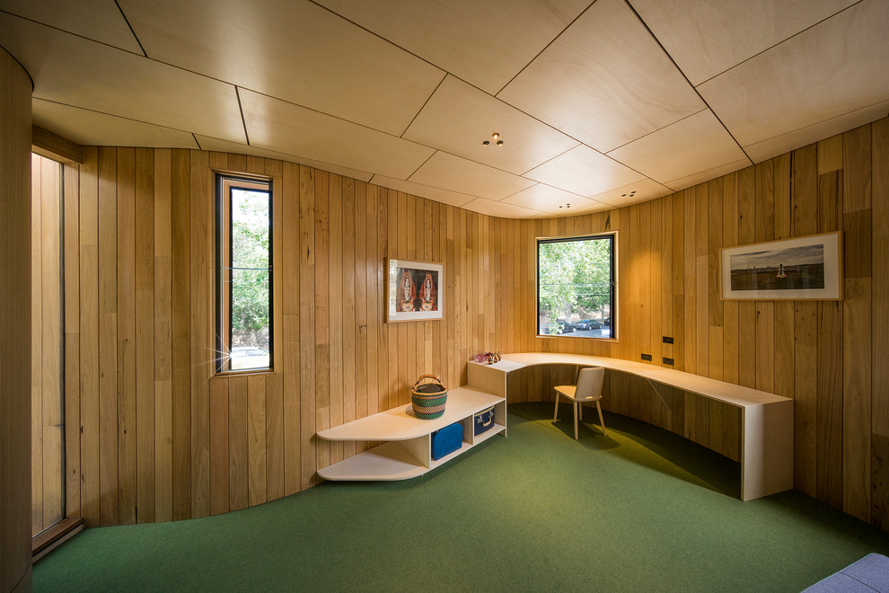 Bild på ett mellanstort funkis hemmabibliotek, med gula väggar, heltäckningsmatta, ett inbyggt skrivbord och grönt golv