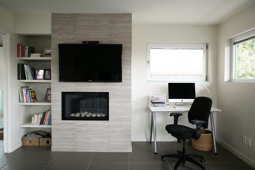 На фото: большой кабинет в стиле модернизм с серыми стенами, полом из керамической плитки, стандартным камином и фасадом камина из камня
