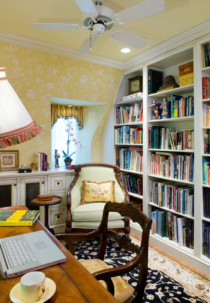 Imagen de despacho clásico pequeño con paredes amarillas, suelo de madera en tonos medios y escritorio independiente