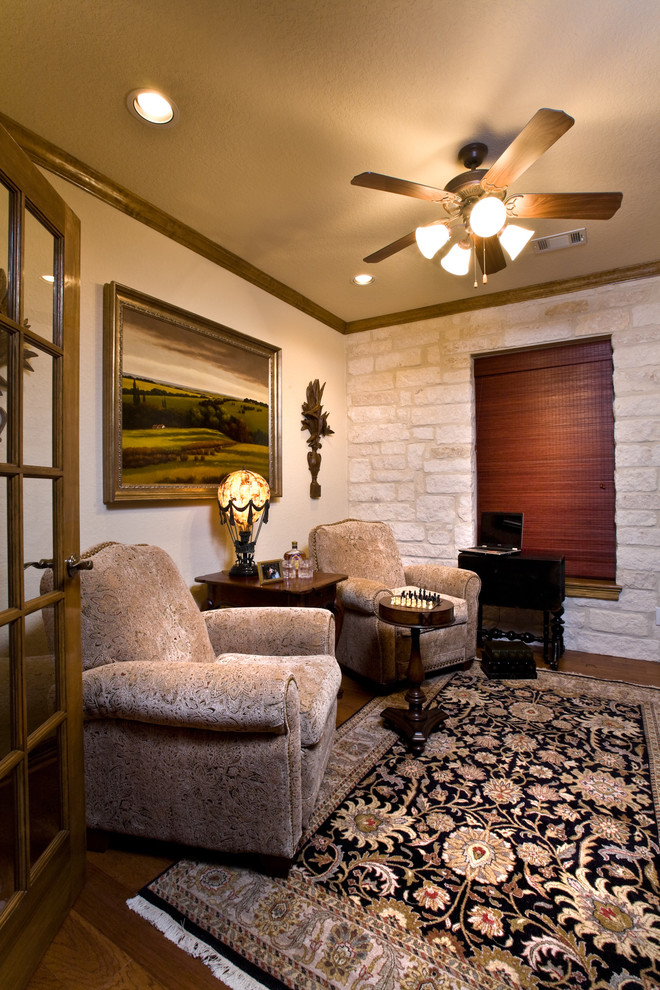 This is an example of a medium sized mediterranean study in Austin with white walls, medium hardwood flooring and no fireplace.