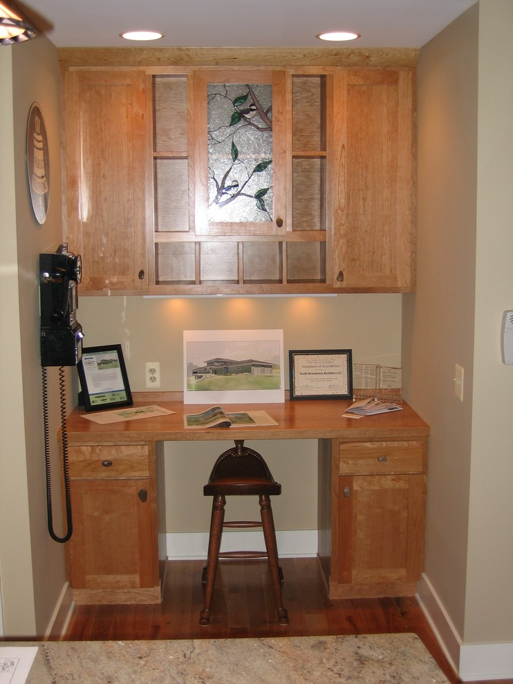 This is an example of a contemporary home office in Grand Rapids with beige walls, medium hardwood flooring and a built-in desk.
