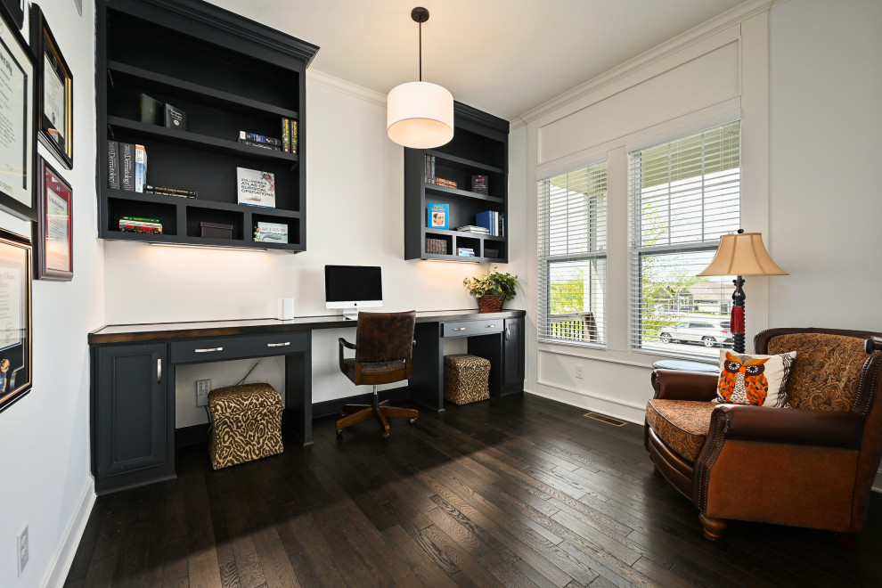 Foto de despacho clásico renovado con paredes blancas, suelo de madera oscura, escritorio empotrado y suelo marrón