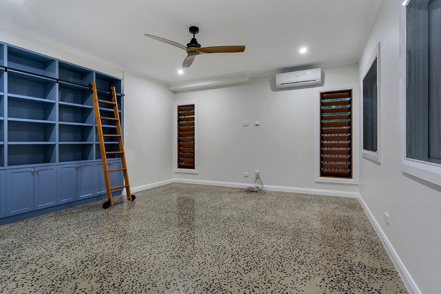Foto di uno studio con libreria, pareti bianche, pavimento in cemento e pavimento grigio