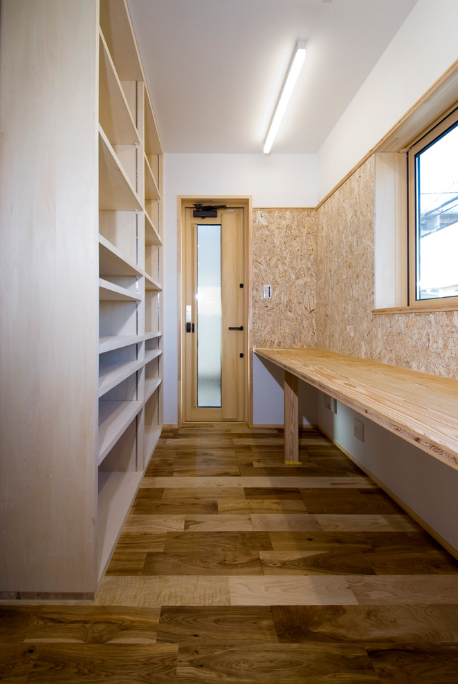 Rustik inredning av ett litet hobbyrum, med vita väggar, ljust trägolv, ett inbyggt skrivbord och brunt golv