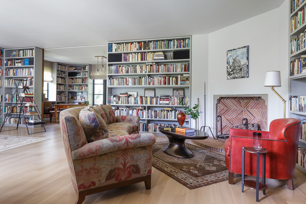 サンフランシスコにある巨大な地中海スタイルのおしゃれな書斎 (白い壁、淡色無垢フローリング、コーナー設置型暖炉、漆喰の暖炉まわり、自立型机、茶色い床) の写真