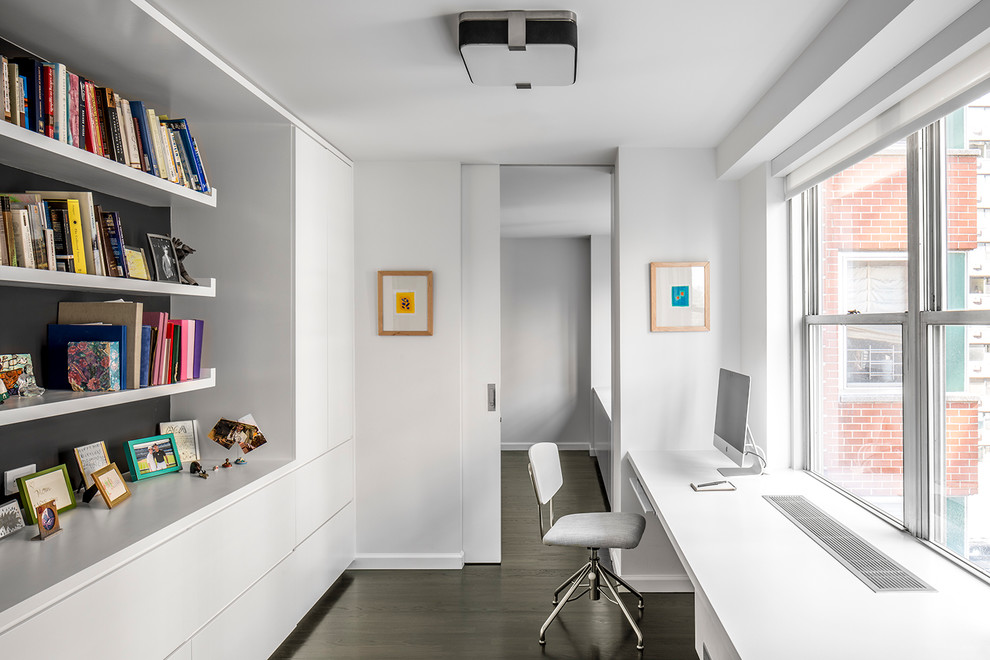 Study room - contemporary built-in desk dark wood floor study room idea in New York with white walls