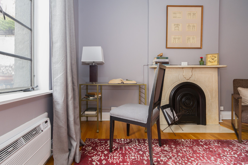 Idéer för ett litet minimalistiskt hemmabibliotek, med blå väggar, mellanmörkt trägolv, en standard öppen spis, en spiselkrans i trä, ett fristående skrivbord och brunt golv