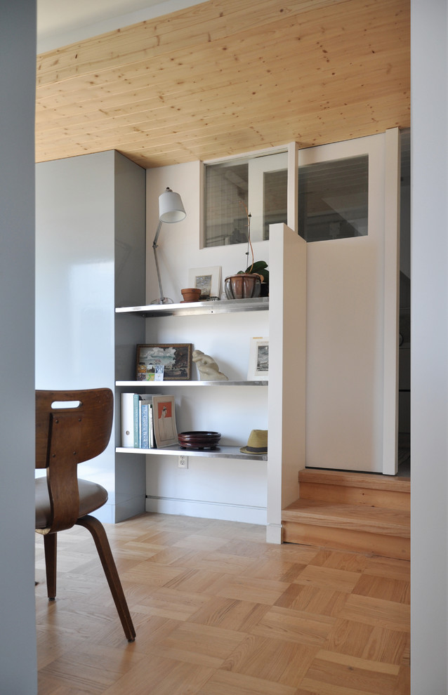 Cette image montre un bureau design avec un mur blanc et un sol en bois brun.