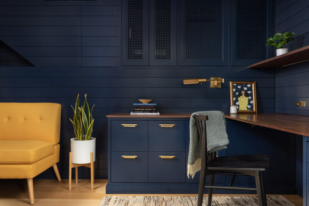 ニューヨークにある小さなトランジショナルスタイルのおしゃれな書斎 (青い壁、淡色無垢フローリング、造り付け机、茶色い床、塗装板張りの壁) の写真