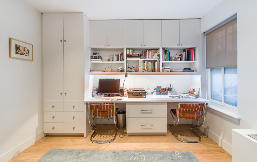 Immagine di un ufficio minimal di medie dimensioni con pareti bianche, parquet chiaro, scrivania incassata, nessun camino e pavimento marrone