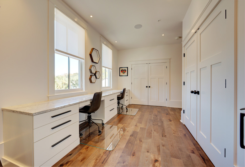 Immagine di uno studio minimal di medie dimensioni con pareti bianche, pavimento in legno massello medio e scrivania incassata