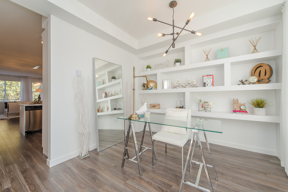 バンクーバーにあるお手頃価格の小さなコンテンポラリースタイルのおしゃれなホームオフィス・書斎 (白い壁、ラミネートの床、暖炉なし、自立型机、茶色い床) の写真