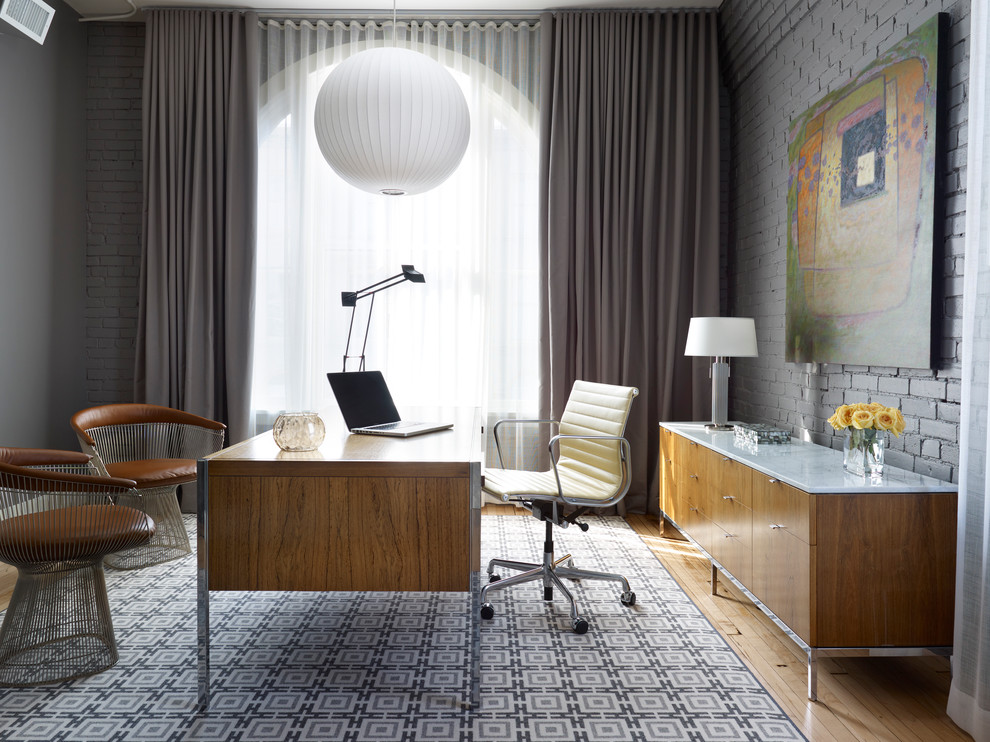 На фото: кабинет в современном стиле с серыми стенами, паркетным полом среднего тона и отдельно стоящим рабочим столом с