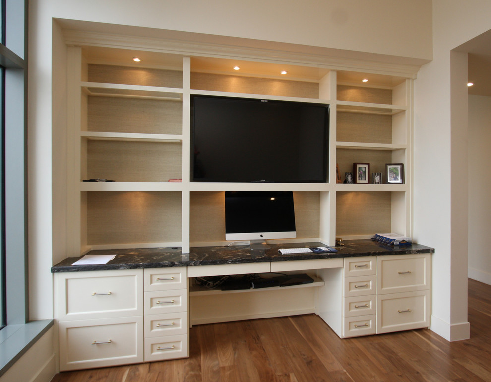 Modelo de despacho actual de tamaño medio con paredes beige, suelo de madera en tonos medios y escritorio empotrado