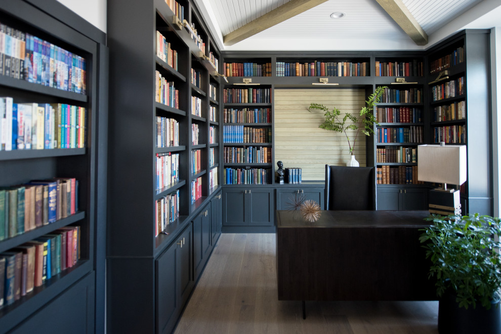 Imagen de despacho moderno de tamaño medio sin chimenea con biblioteca, suelo de madera oscura y escritorio independiente