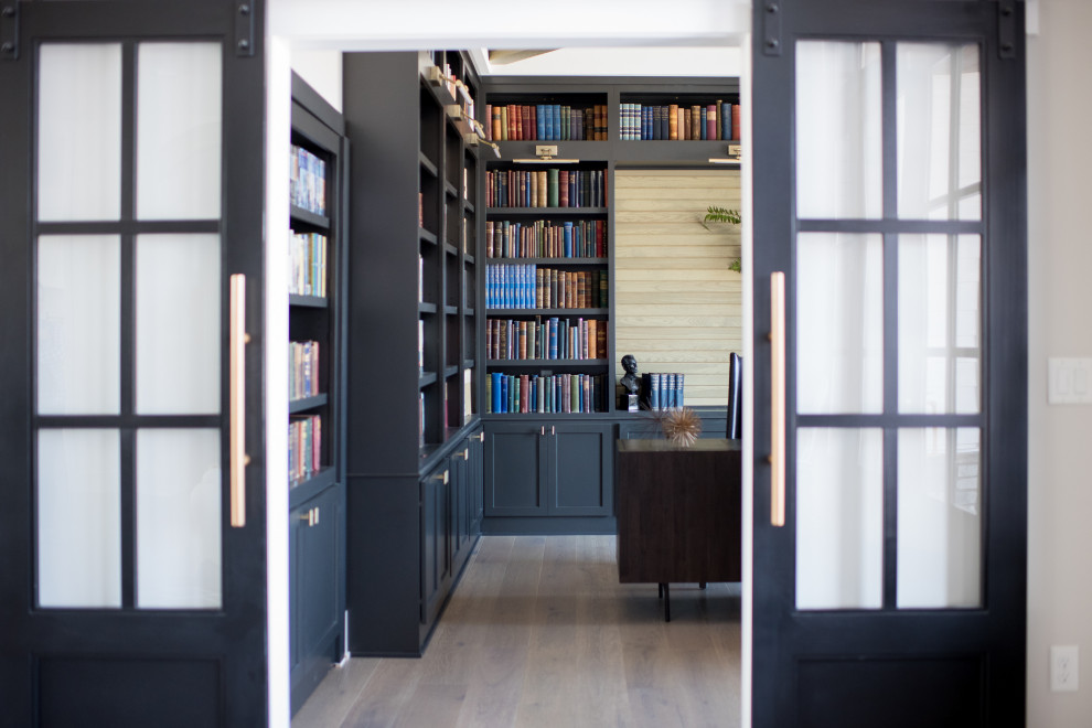 Ejemplo de despacho minimalista de tamaño medio sin chimenea con biblioteca, suelo de madera oscura y escritorio independiente